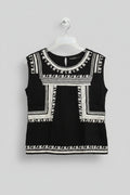 Black dress with white embroidery on a hanger against a colorful background
